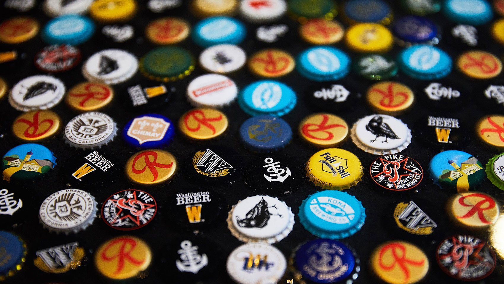 various beer bottle caps spread out on table 